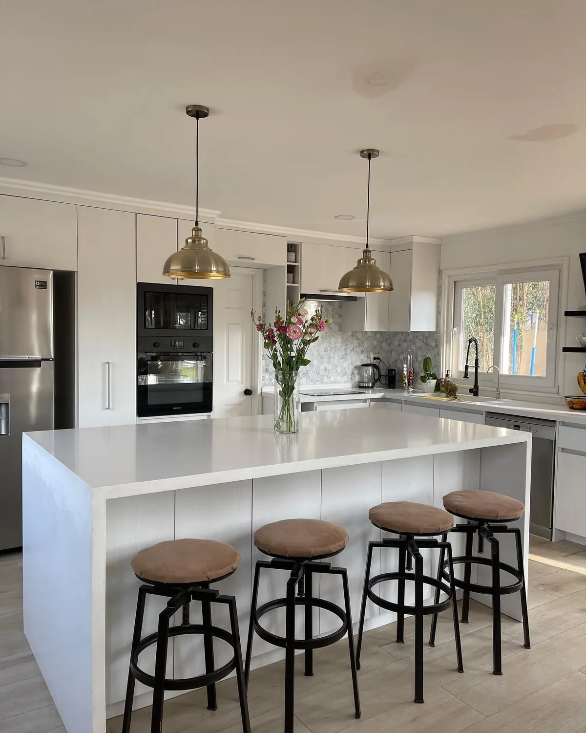 Cocina blanca con isla y pisos de madera en una casa de La Foresta de Zapallar