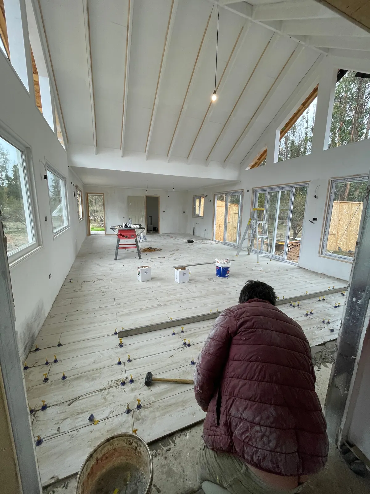 Interior en obra con cielo a dos aguas y maestro trabajando en el piso