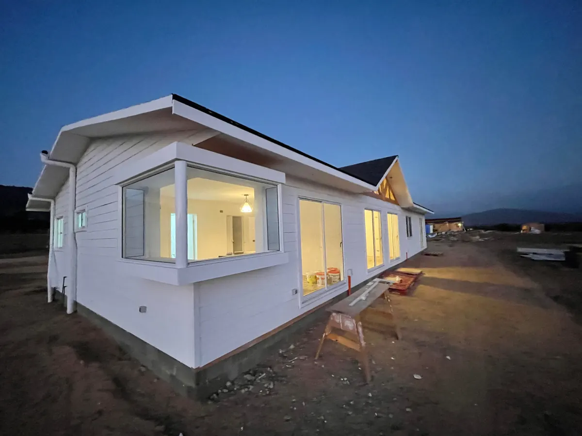 Casa blanca con ventana en bow window al anochecer, Parcela I-5, La Foresta de Zapallar