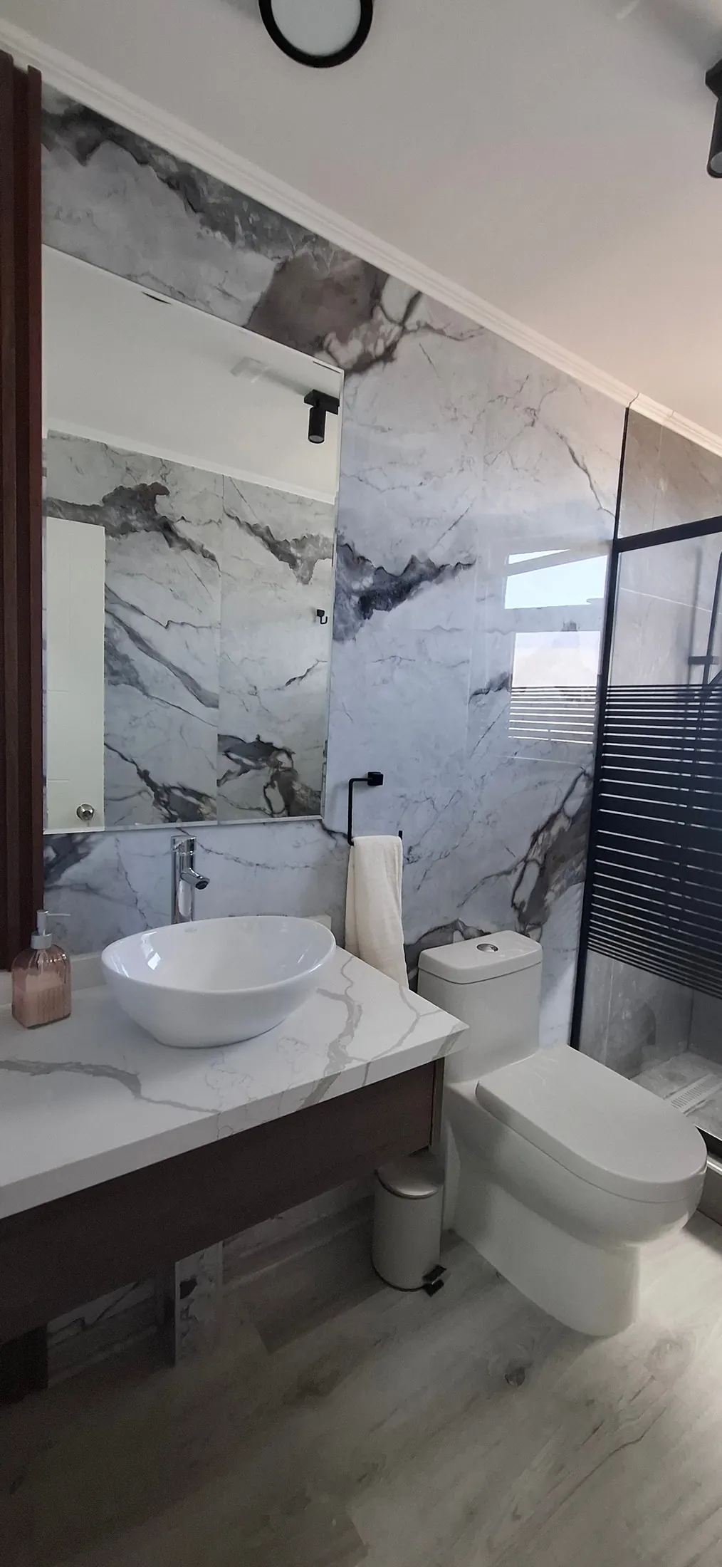 Baño de Casa Mantagua con muro de porcelanato símil mármol y listones de madera
