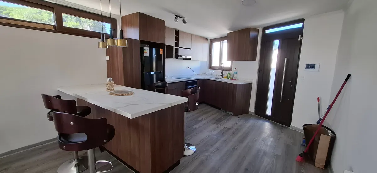 Cocina de Casa Mantagua con isla de cubierta blanca y muebles de madera oscura