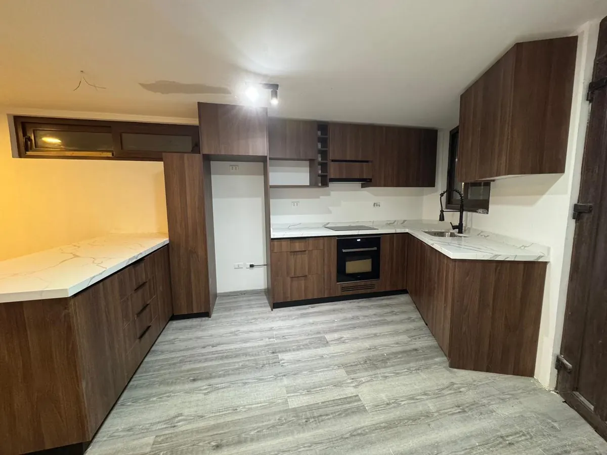 Cocina en L de Casa Mantagua con muebles de madera y cubierta de mármol