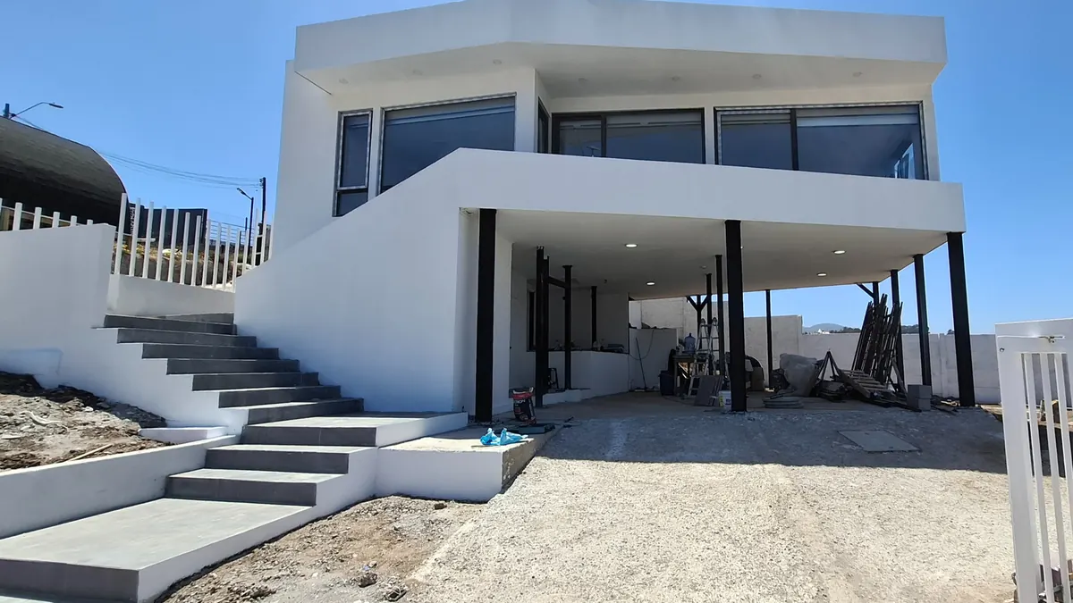 Casa Mantagua: volumen blanco de dos pisos con escalera exterior y terraza en primera línea