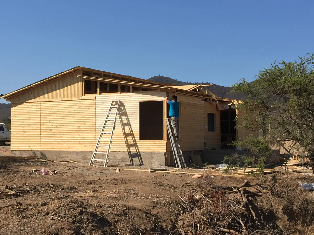 Casa V-26 en obra con andamio y revestimiento de madera en proceso